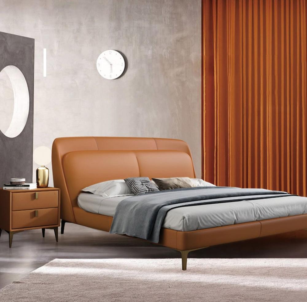 Cognac leather upholstered bed with a curved headboard in a bedroom with orange curtains